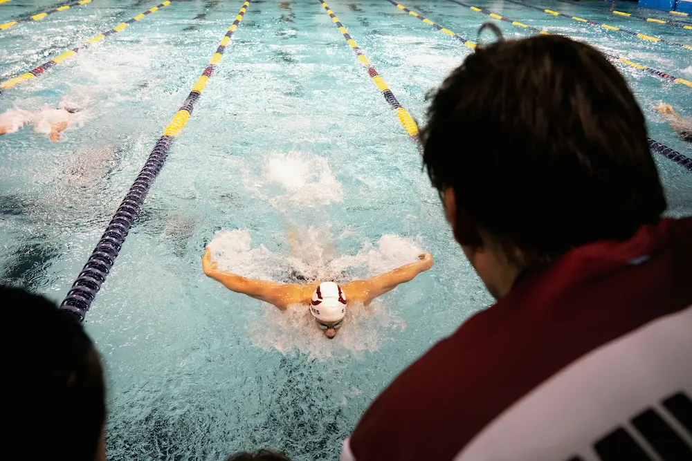 Young age-group swimmer performing butterfly with both arms recovering low over the water