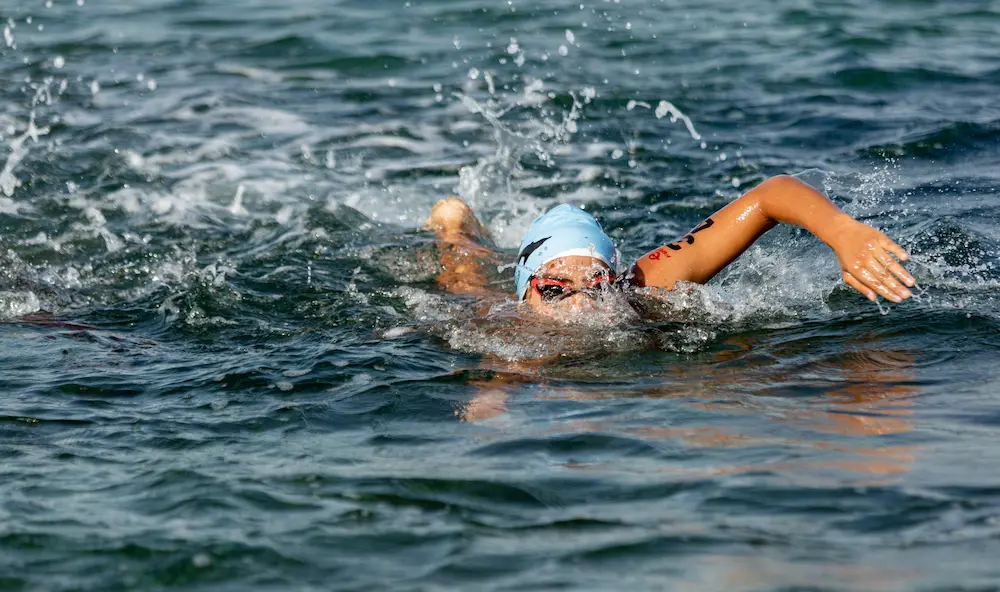 Open-water swimmer sighting forward towards a marker buoy in a lake